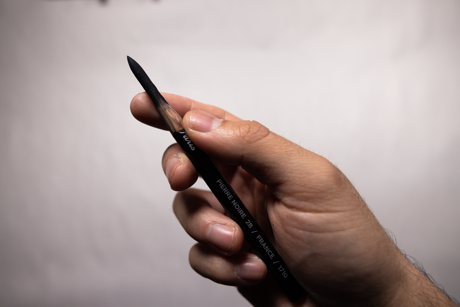 Hand holding a drawing pencil against a clean background, illustrating art tools and creator workflow