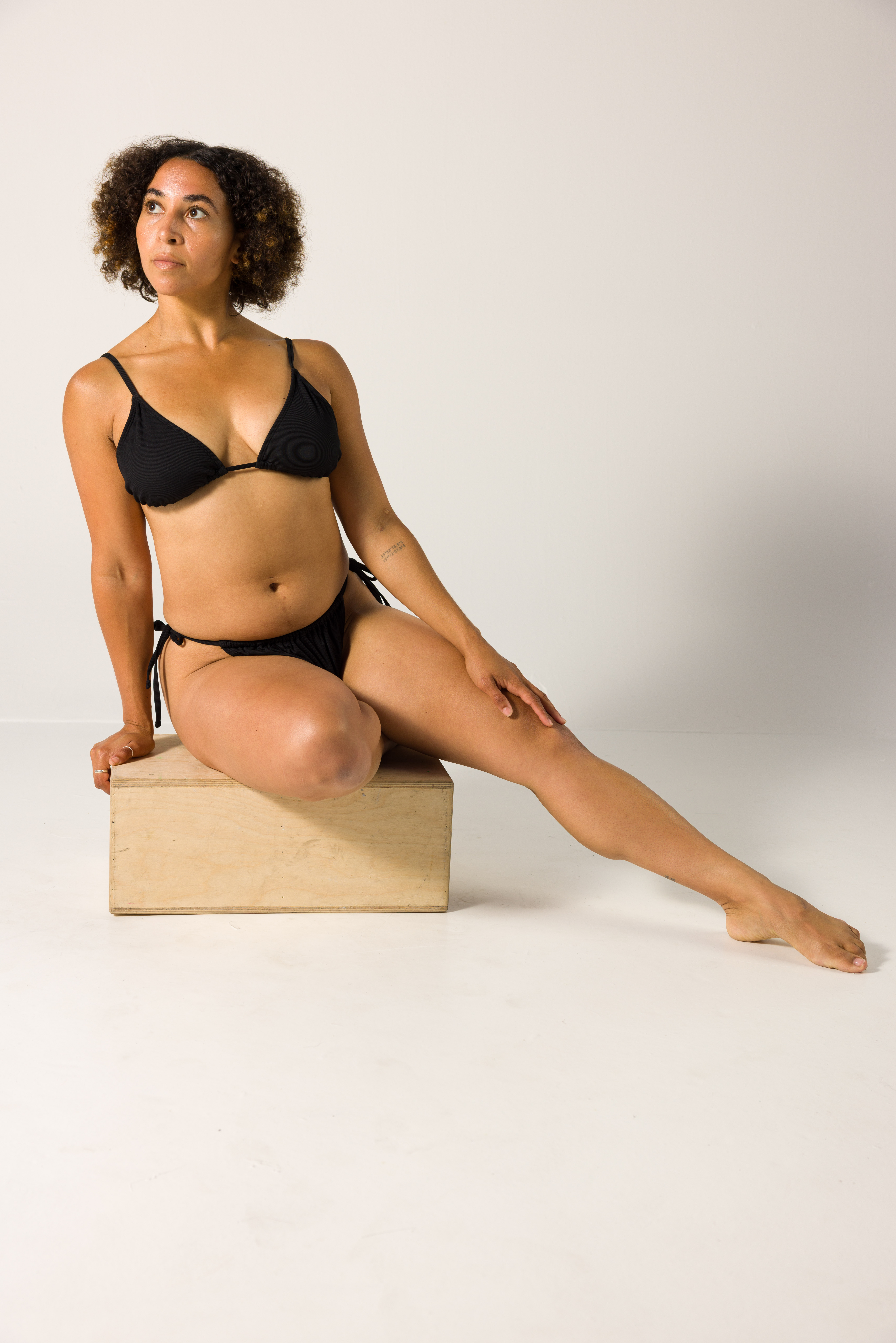 Seated figure drawing reference pose on a box with one leg extended forward
