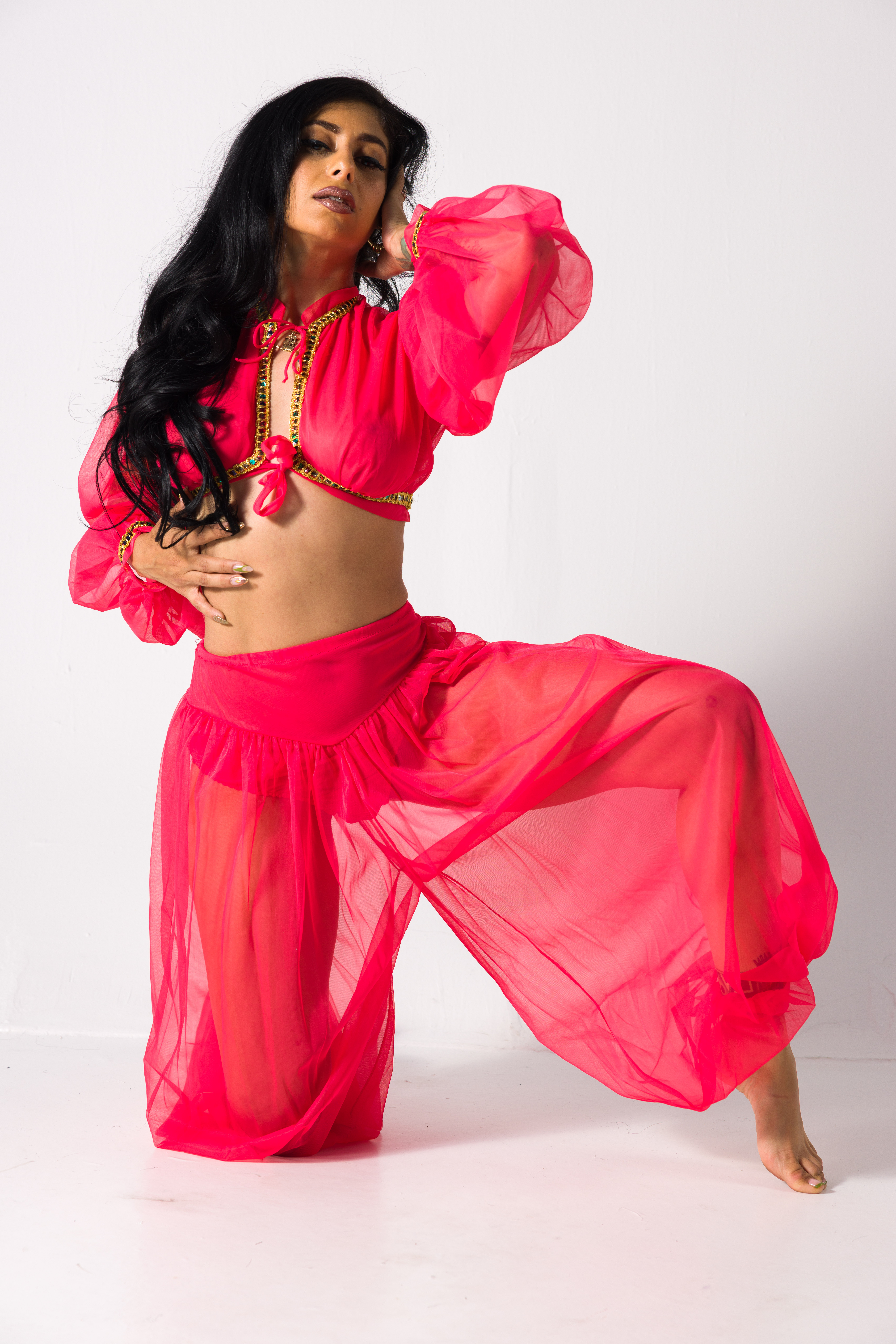 Kneeling costume pose reference in a flowing bright pink outfit with one knee lifted