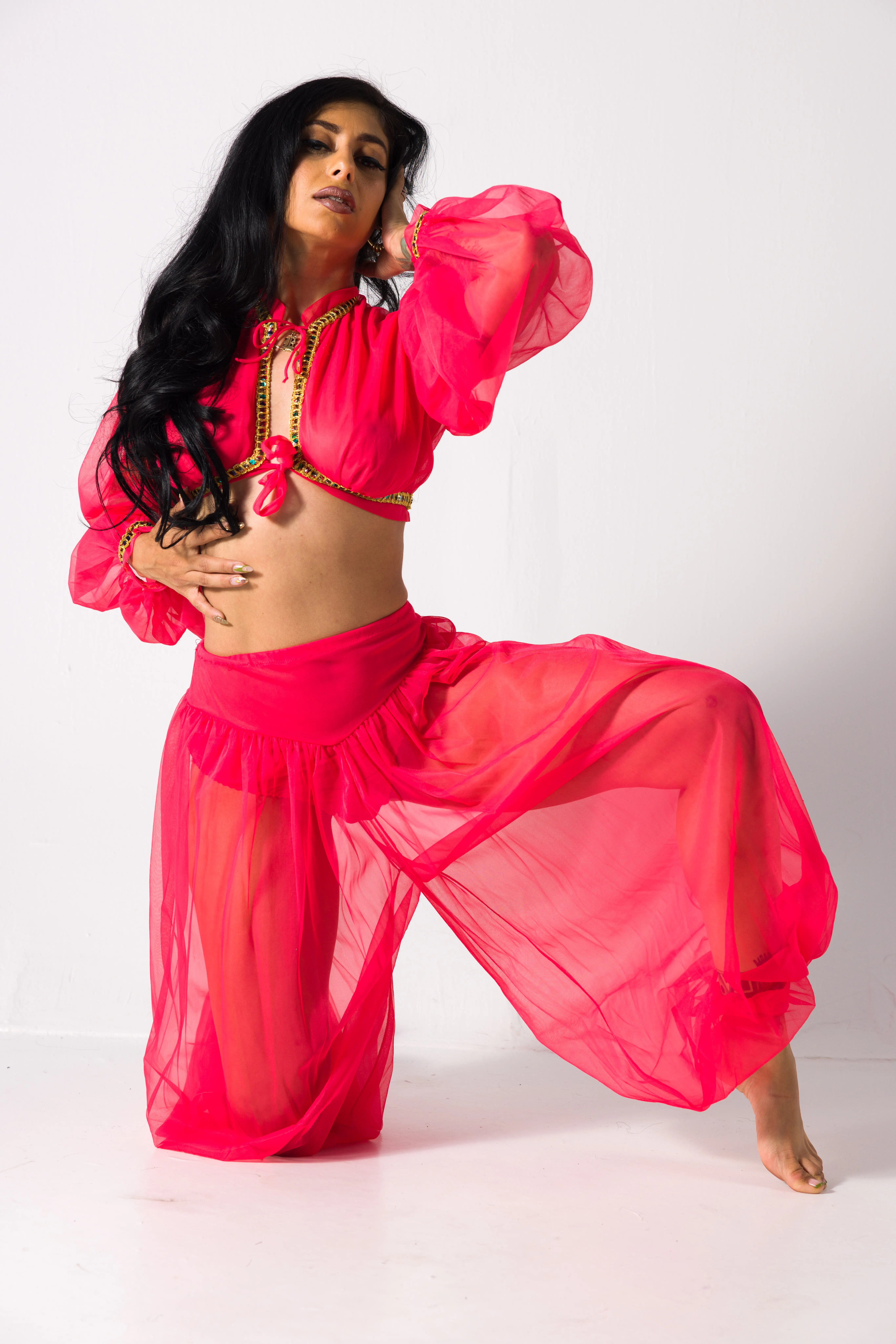 Kneeling costume pose reference in a flowing bright pink outfit with one knee lifted